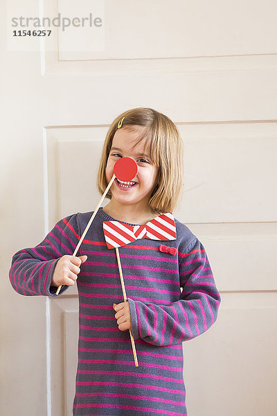 Porträt des kleinen Mädchens mit Spielzeugbogen und roter Nase