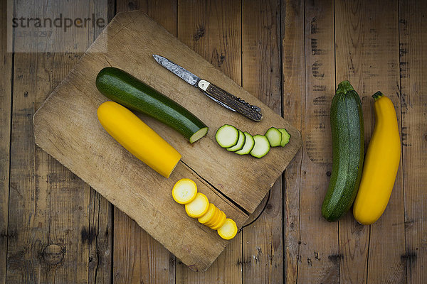 Ganze und geschnittene gelbe und grüne Zucchini auf Holz