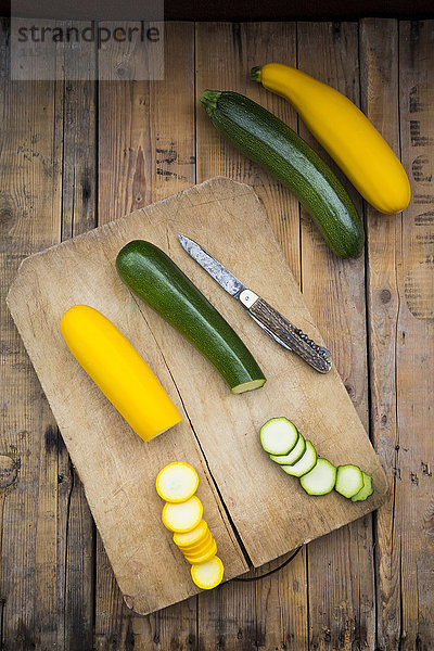 Ganze und geschnittene gelbe und grüne Zucchini auf Holz