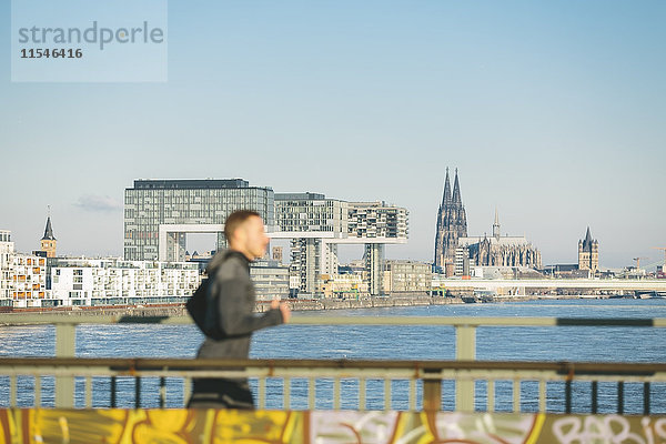 Deutschland  Köln  Junger Mann am Flussufer