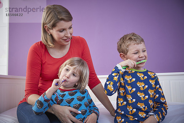 Mutter mit zwei Kindern beim Zähneputzen