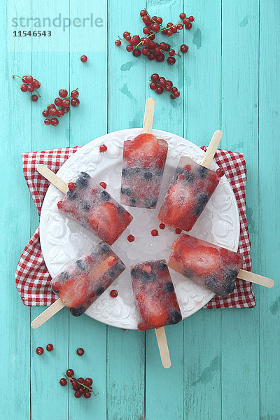 Früchte-Eis-Lolly mit frischen Beeren auf einem Teller