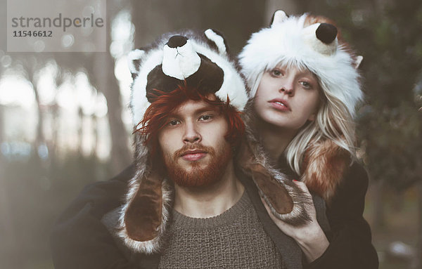 Porträt eines jungen Paares mit Tierhüten im Wald