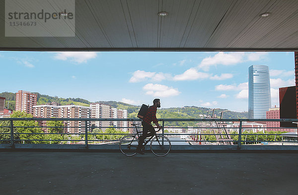 Spanien  Bilbao  Mann mit Rennrad auf einer Brücke