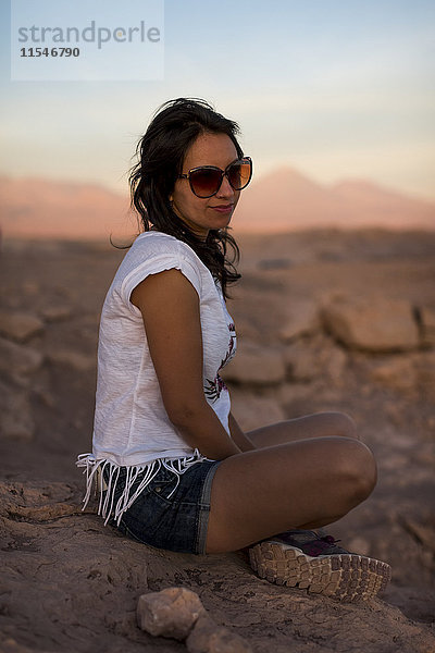 Chile  San Pedro de Atacama  Frau auf Felsen in der Atacama-Wüste sitzend