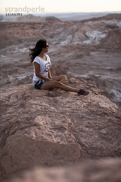 Chile  San Pedro de Atacama  Frau auf Felsen in der Atacama-Wüste sitzend