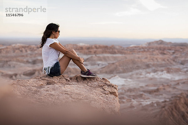 Chile  San Pedro de Atacama  Frau auf Felsen in der Atacama-Wüste sitzend