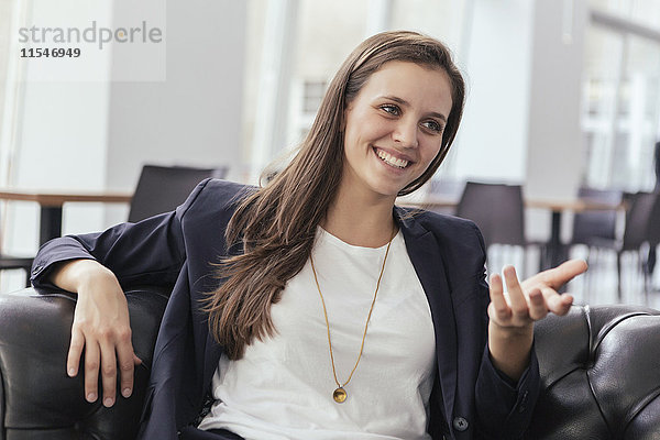 Porträt einer lächelnden jungen Geschäftsfrau im Gespräch mit jemandem