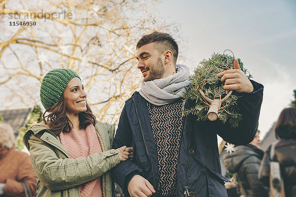 Glückliches Paar mit einem Baum auf dem Weihnachtsmarkt