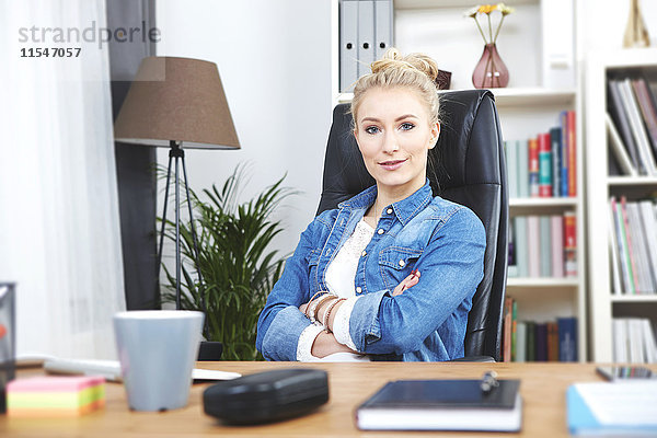 Porträt einer selbstbewussten  blonden Geschäftsfrau am Schreibtisch in ihrem Home-Office