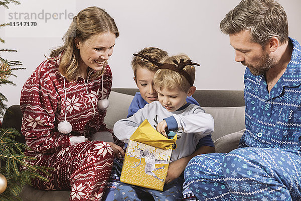 Eltern beobachten Sohn beim Auspacken eines Weihnachtsgeschenks