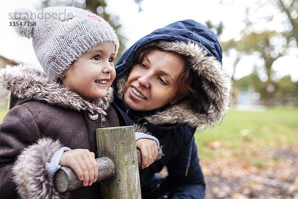 Porträt eines glücklichen kleinen Mädchens mit ihrer Mutter auf einem Spielplatz im Herbst