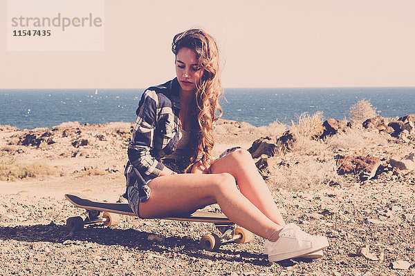 Spanien  Teenager-Mädchen auf Longboard sitzend