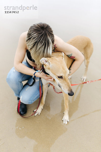 Spanien  Llanes  junge Frau mit ihrem Windhund am Strand