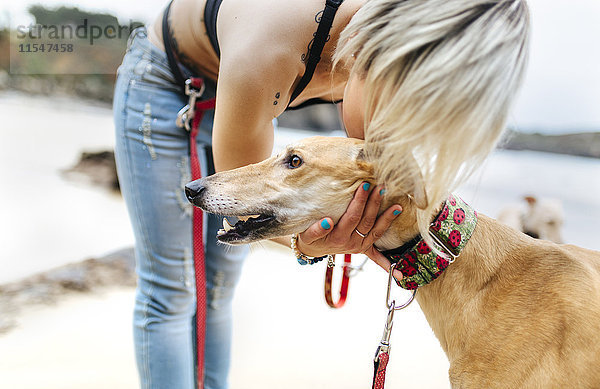 Spanien  Llanes  junge Frau mit ihrem Windhund am Strand