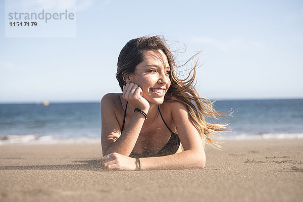 Spanien  Teneriffa  Porträt einer jungen Frau  die sich am Strand entspannt