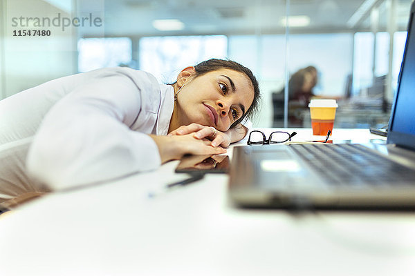 Junge Frau langweilig an ihrem Schreibtisch im Büro