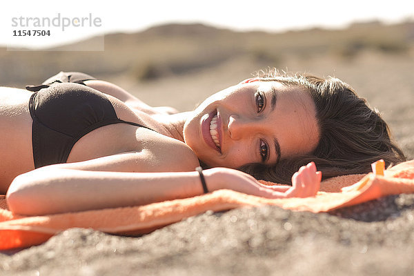 Spanien  Teneriffa  Portrait einer jungen Frau am Strand liegend