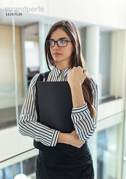 Porträt einer jungen Frau mit schwarzer Akte im Büro