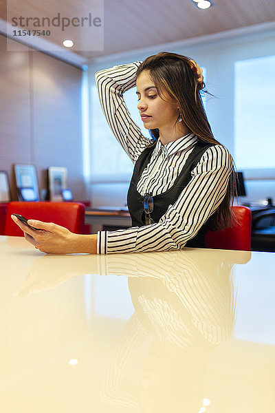 Geschäftsfrau im Konferenzraum mit Blick auf ihr Smartphone