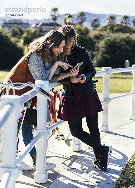 Zwei junge Frauen im Freien beim Blick auf das Handy