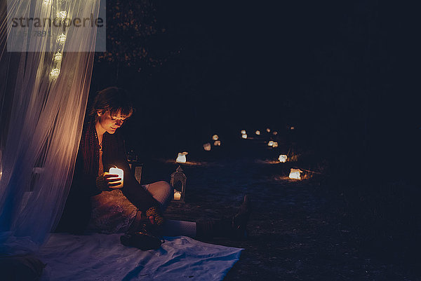 Frau in einem romantischen Lager bei Kerzenlicht in der Natur