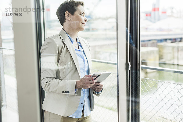 Geschäftsfrau mit digitalem Tablett am Fenster