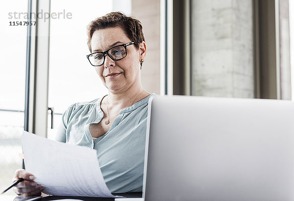 Geschäftsfrau beim Lesen von Dokumenten am Schreibtisch im Büro