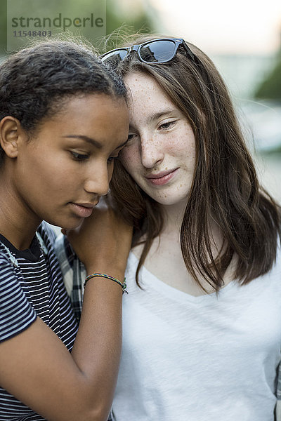Zwei Mädchen im Teenageralter  die sich im Freien nahe stehen.