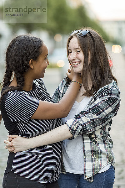 Zwei fröhliche Teenager-Mädchen  die sich im Freien umarmen.