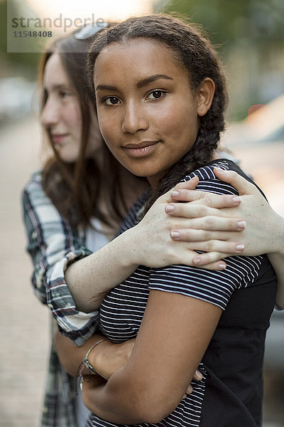 Zwei jugendliche Mädchen  die sich im Freien umarmen.