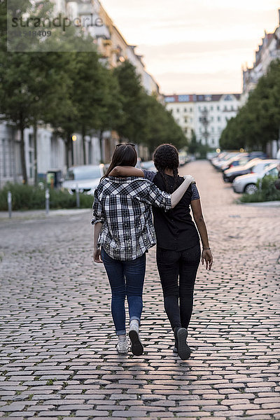 Zwei Mädchen im Teenageralter  die auf einer Straße laufen.