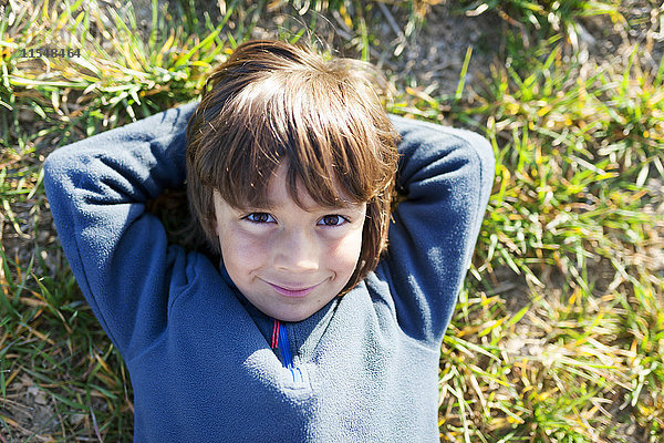 Porträt eines lächelnden Jungen auf einer Wiese sitzend