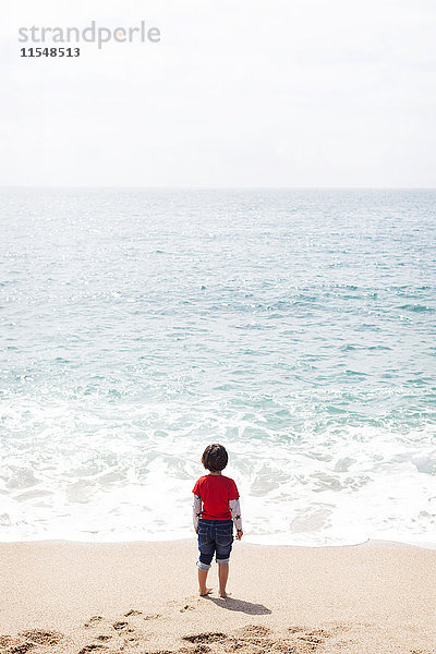 Rückansicht des kleinen Jungen am Strand mit Blick aufs Meer