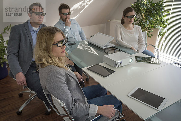 Vier Kollegen mit 3D-Brille bei einer Präsentation mit Projektor im Konferenzraum