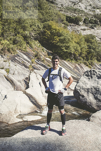 Spanien  A Capela  Porträt eines lächelnden Langläufers auf einem Felsen stehend