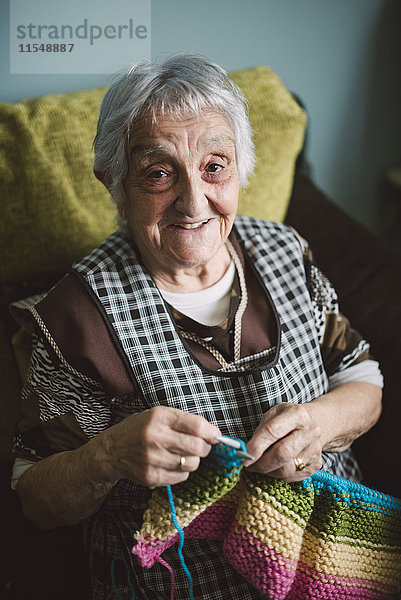 Porträt einer lächelnden Seniorin mit Strickerei