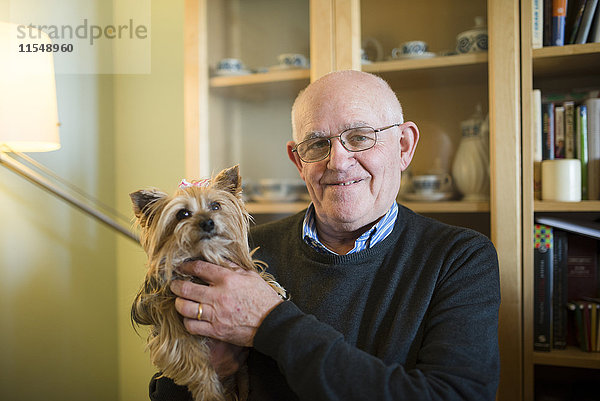 Porträt eines älteren Mannes mit seinem Yorkshire Terrier zu Hause