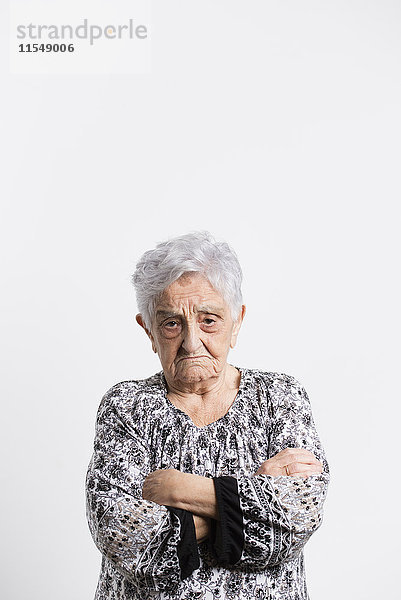 Porträt der wütenden Seniorin vor weißem Hintergrund