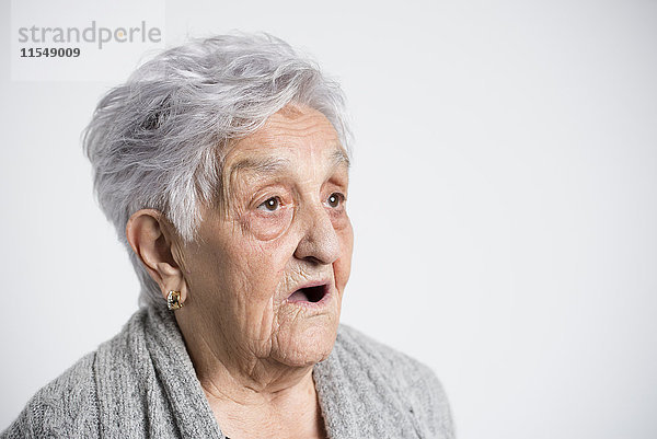 Porträt der überraschten Seniorin vor weißem Hintergrund