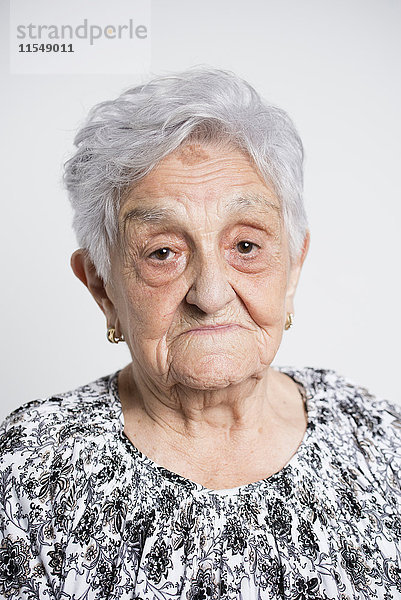Porträt der traurigen Seniorin vor weißem Hintergrund