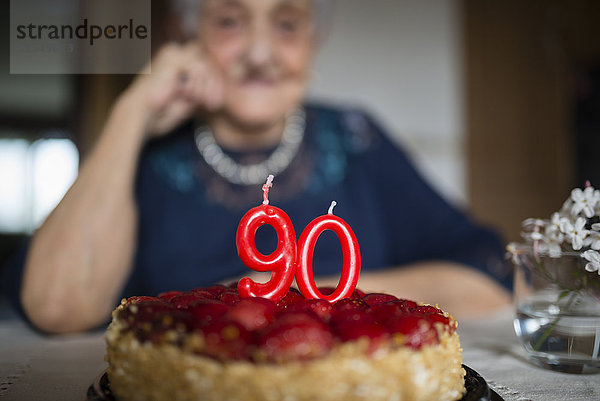 Kerzen auf einem Geburtstagskuchen einer älteren Frau  die ihren neunzigsten Geburtstag feiert.