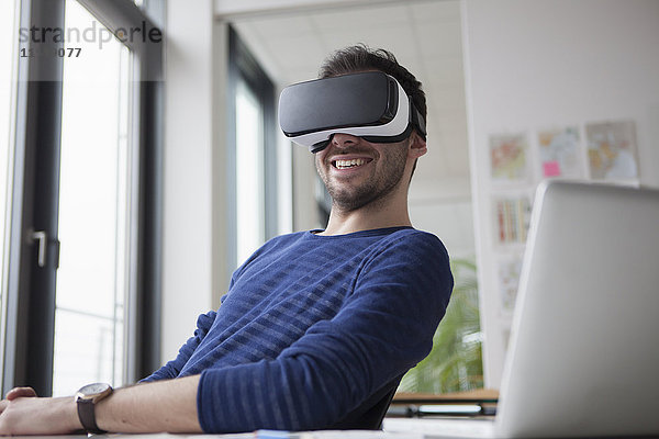 Lächelnder Mann mit Virtual Reality Brille im Büro