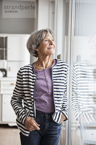 Porträt einer selbstbewussten Seniorin mit Blick durchs Fenster