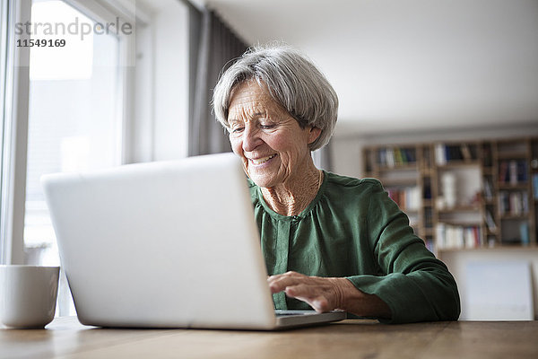 Porträt einer älteren Frau mit Laptop zu Hause