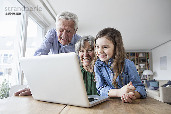 Die Großeltern und ihre Enkelin haben Spaß mit dem Laptop zu Hause.