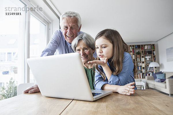 Großeltern und ihre Enkelin skyping mit Laptop zu Hause
