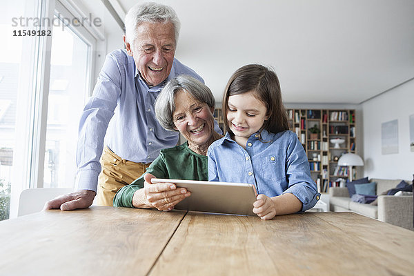 Großeltern und ihre Enkelin mit digitalem Tablett zu Hause