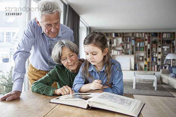Großeltern beim Betrachten des Fotoalbums mit ihrer Enkelin zu Hause