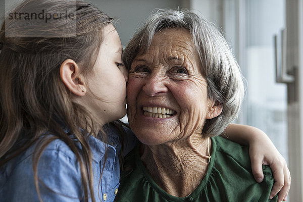 Kleines Mädchen  das seine Großmutter küsst.